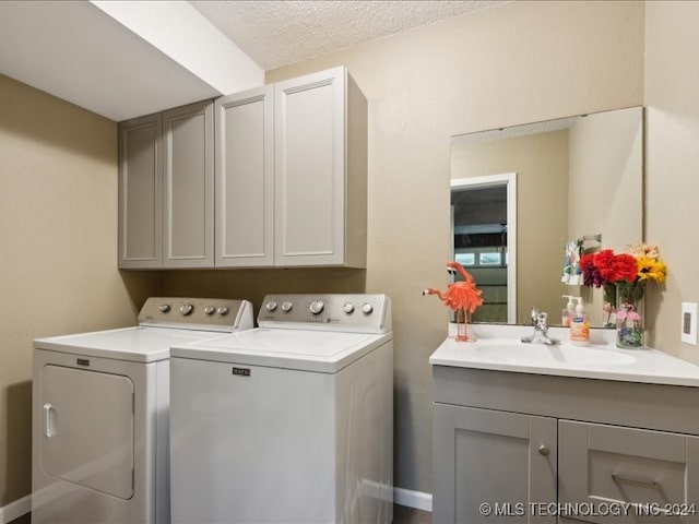 laundry area featuring cabinets, a textured ceiling, sink, and washing machine and dryer