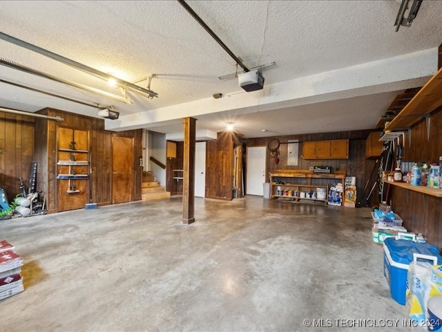 garage with a garage door opener, a workshop area, and wooden walls