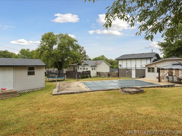 view of yard with a trampoline, a covered pool, a storage shed, a patio area, and a gazebo