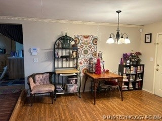 dining space with hardwood / wood-style floors, a chandelier, and ornamental molding