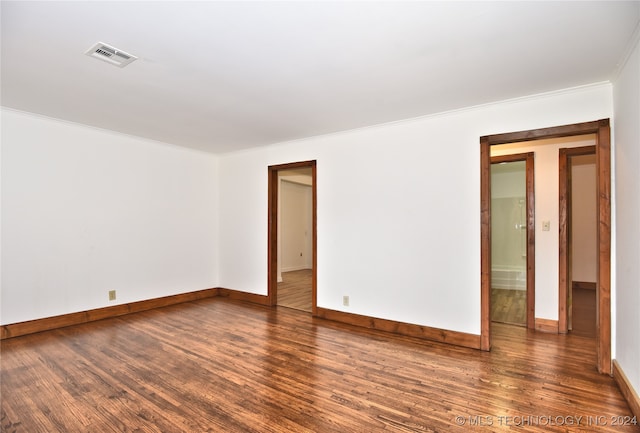 empty room with dark wood-type flooring and crown molding