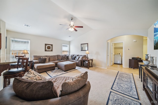 living room with vaulted ceiling, ceiling fan, light colored carpet, and a healthy amount of sunlight