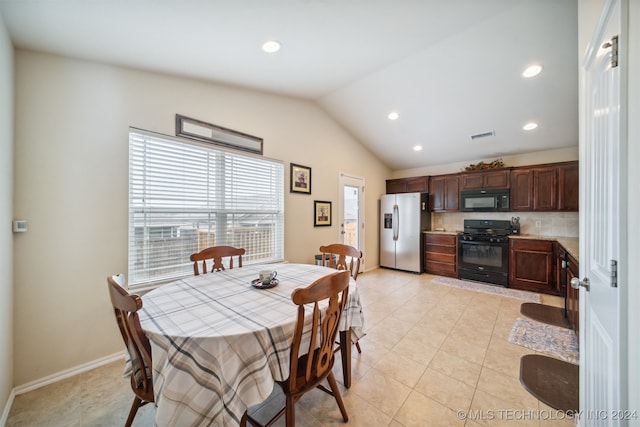 dining area with light tile patterned floors and vaulted ceiling