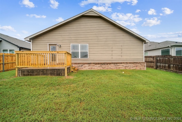 back of property with a deck and a yard