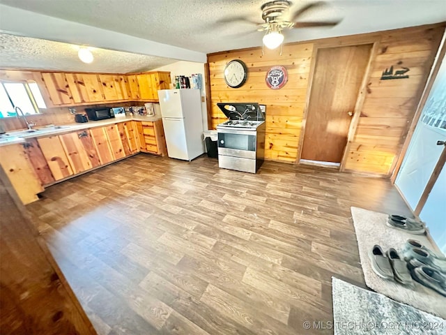 kitchen with ceiling fan, wood walls, light hardwood / wood-style flooring, stainless steel range oven, and white fridge