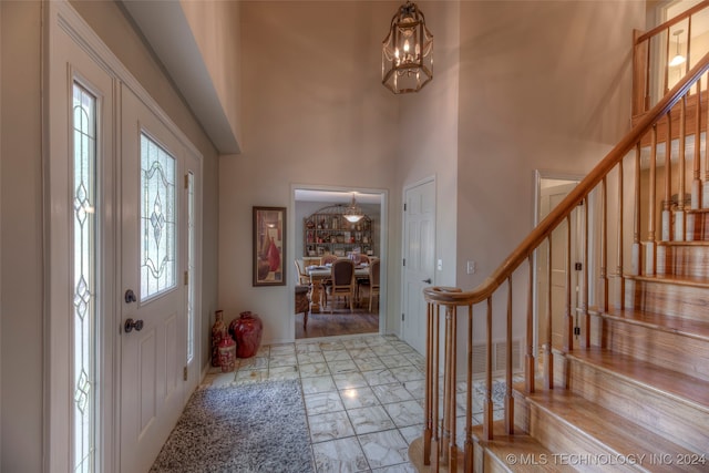 foyer entrance with a notable chandelier, a towering ceiling, and light hardwood / wood-style floors