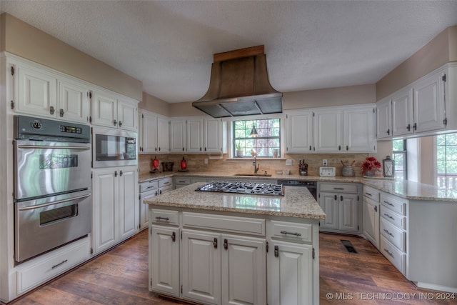 kitchen with a center island, dark hardwood / wood-style floors, white cabinetry, appliances with stainless steel finishes, and premium range hood