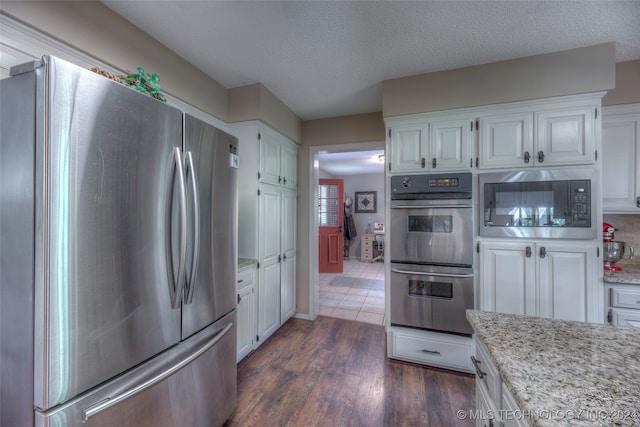 kitchen featuring stainless steel appliances, white cabinets, a textured ceiling, and dark hardwood / wood-style flooring