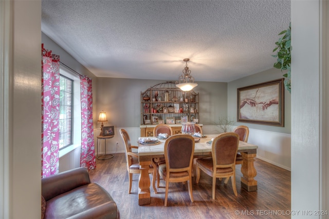 dining area featuring wood-type flooring and a textured ceiling