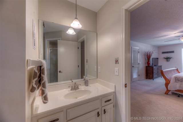 bathroom featuring a textured ceiling, a shower with door, ceiling fan, and vanity