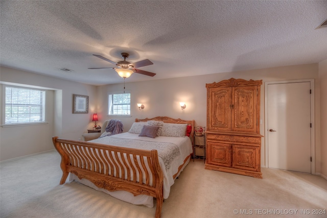 carpeted bedroom with ceiling fan, a textured ceiling, and multiple windows