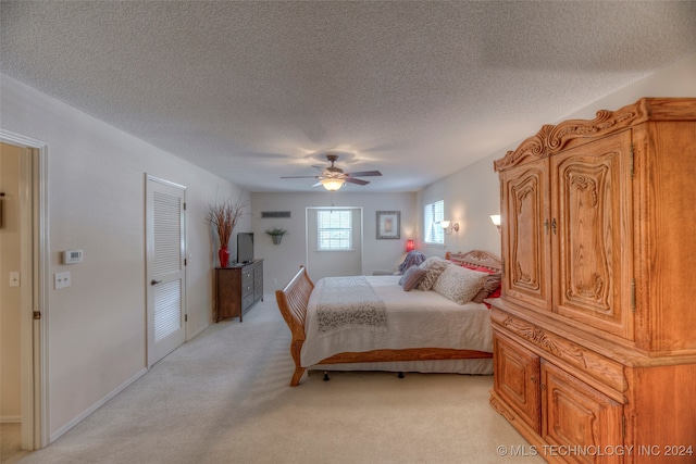 carpeted bedroom with ceiling fan, a textured ceiling, and a closet