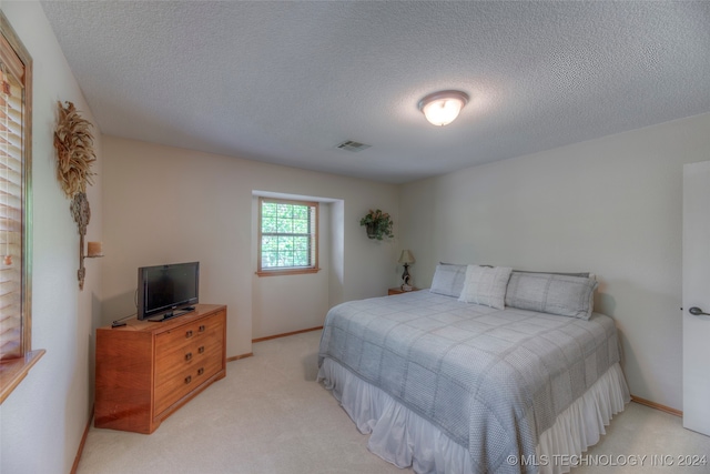 bedroom featuring a textured ceiling and light colored carpet