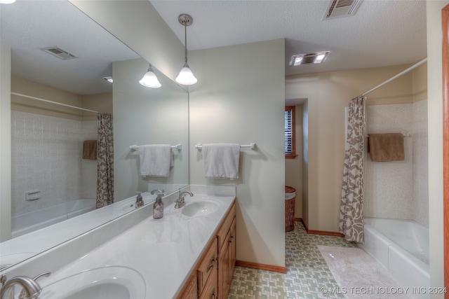 bathroom with shower / bath combo with shower curtain, a textured ceiling, and vanity