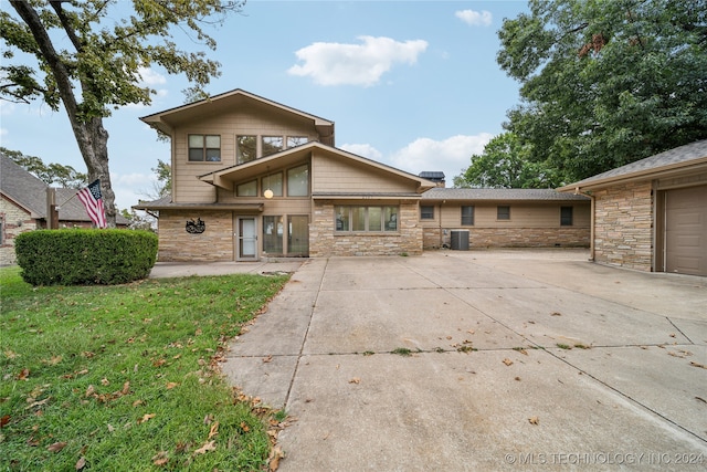 back of house featuring a lawn, cooling unit, and a garage