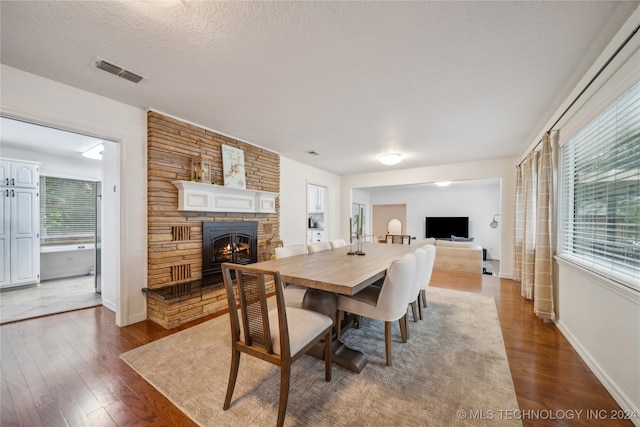 dining area with dark hardwood / wood-style floors, plenty of natural light, and a fireplace