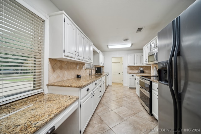 kitchen with white cabinets, stainless steel appliances, tasteful backsplash, and light stone countertops