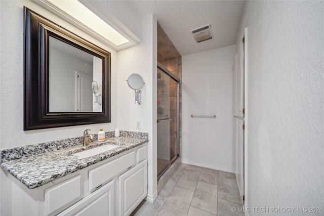 bathroom featuring tile patterned floors, a textured ceiling, a shower with door, and vanity