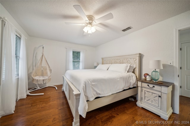 bedroom featuring a textured ceiling, ceiling fan, and dark hardwood / wood-style flooring