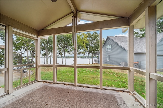 unfurnished sunroom with vaulted ceiling with beams and a water view