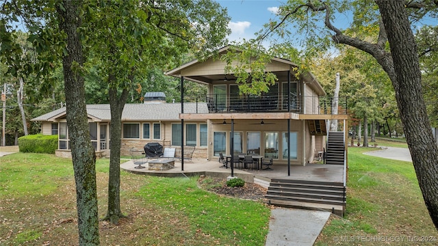 exterior space featuring a wooden deck, a front lawn, a patio area, and an outdoor fire pit