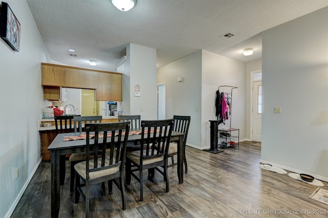 dining area with a textured ceiling and dark wood-type flooring