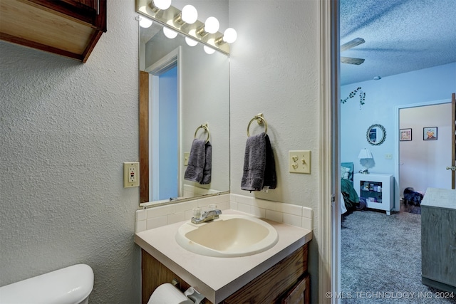 bathroom featuring a textured ceiling, vanity, and toilet