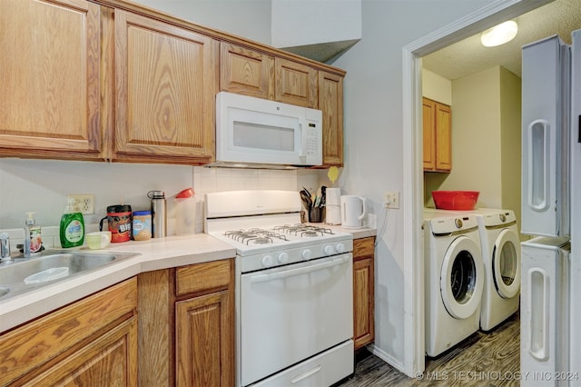 kitchen featuring sink, white appliances, backsplash, washing machine and dryer, and dark hardwood / wood-style flooring