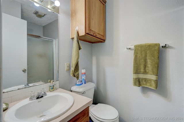 bathroom with a textured ceiling, backsplash, a shower with door, vanity, and toilet