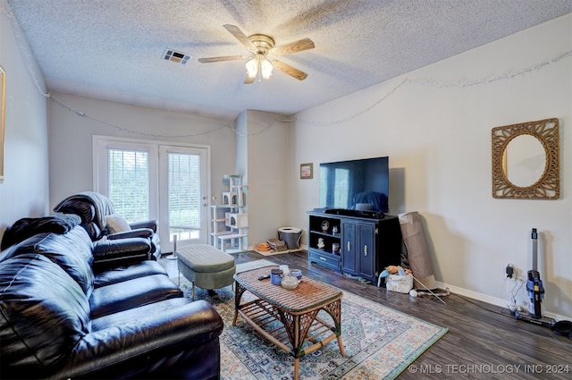 living room featuring ceiling fan, a textured ceiling, and dark wood-type flooring