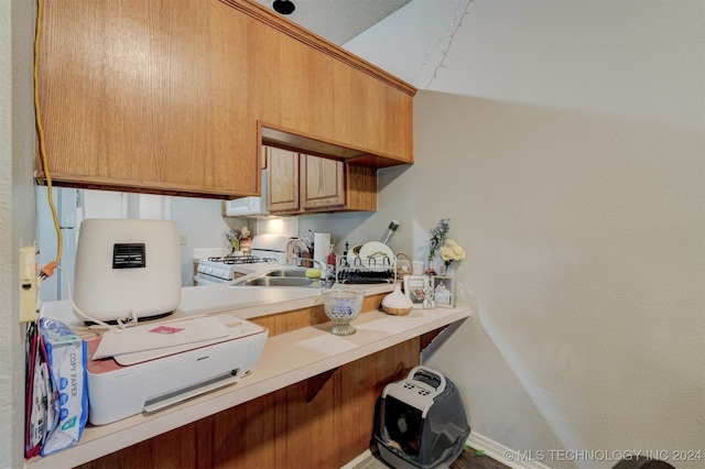 kitchen with white range with gas stovetop, a textured ceiling, and sink