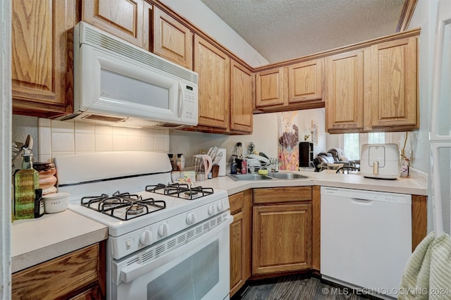 kitchen featuring white appliances, a textured ceiling, and sink