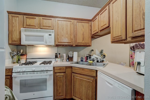 kitchen with white appliances, a textured ceiling, tasteful backsplash, and sink