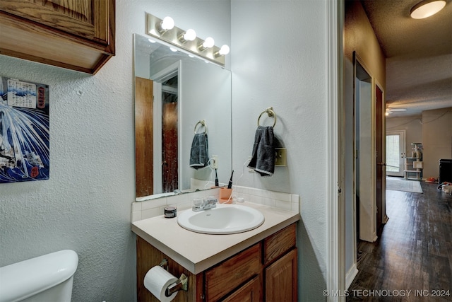 bathroom featuring vanity, a textured ceiling, wood-type flooring, ceiling fan, and toilet