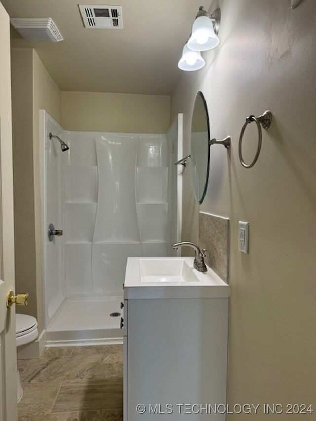 bathroom featuring walk in shower, vanity, and toilet