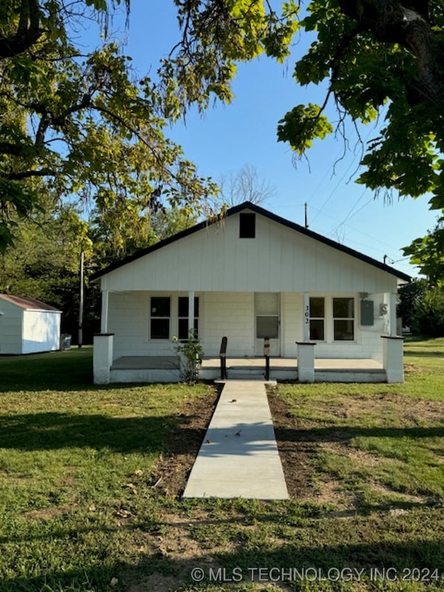 view of front facade featuring a front lawn, an outdoor structure, and covered porch