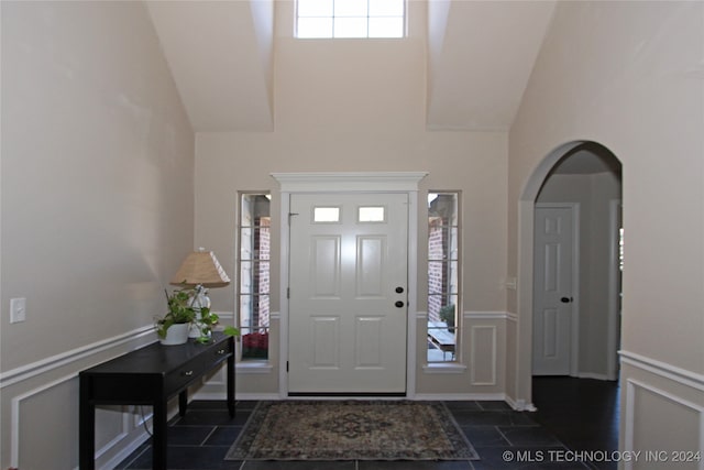 entrance foyer featuring high vaulted ceiling and dark tile patterned flooring