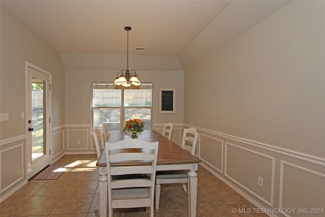 unfurnished dining area with an inviting chandelier, tile patterned floors, vaulted ceiling, and a healthy amount of sunlight