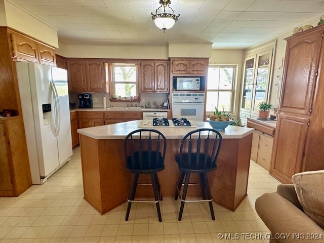 kitchen featuring a breakfast bar, sink, white appliances, and a center island