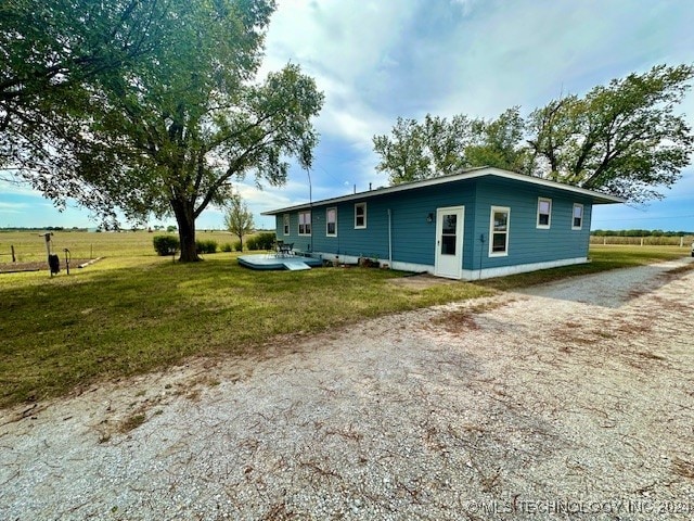 back of property featuring a yard and a rural view