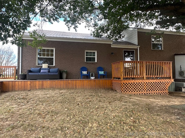 rear view of property featuring a wooden deck, an outdoor hangout area, and a lawn