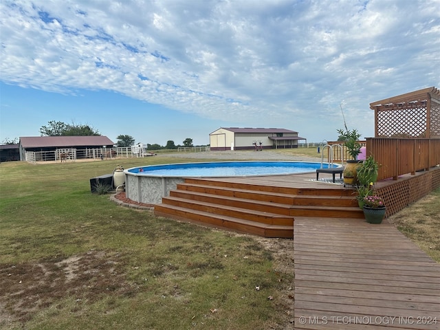 view of pool with a wooden deck, a shed, and a lawn