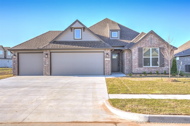 view of front of property with a front yard, cooling unit, and a garage