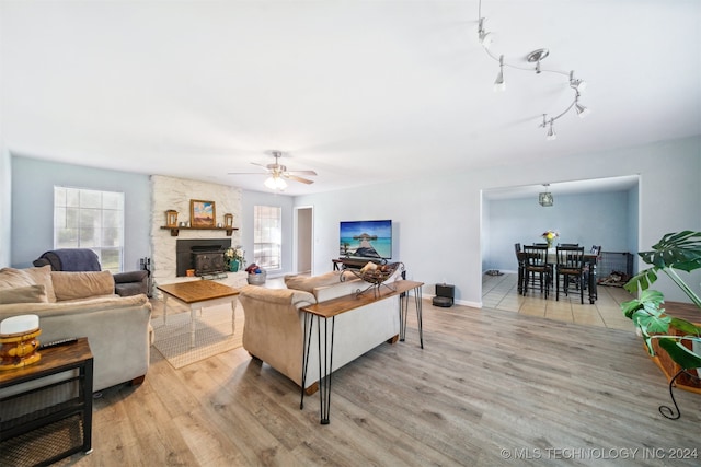 living room featuring ceiling fan, a healthy amount of sunlight, a fireplace, and light wood-type flooring