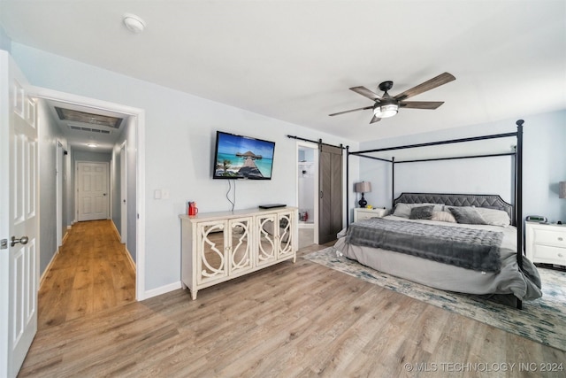 bedroom featuring light hardwood / wood-style floors, a barn door, and ceiling fan