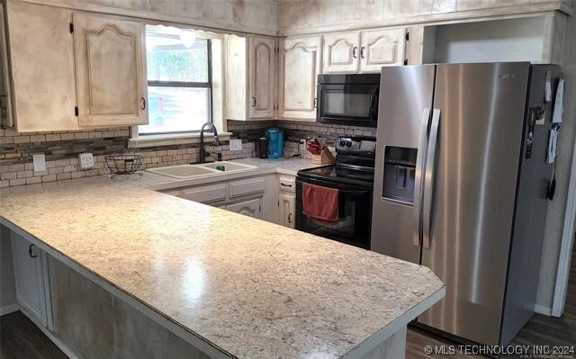 kitchen with sink, kitchen peninsula, tasteful backsplash, and black appliances