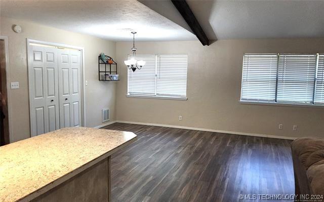 dining room featuring a chandelier, beamed ceiling, and dark hardwood / wood-style flooring