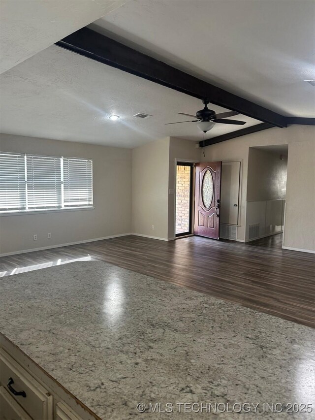 unfurnished living room featuring dark wood-type flooring, visible vents, baseboards, and ceiling fan