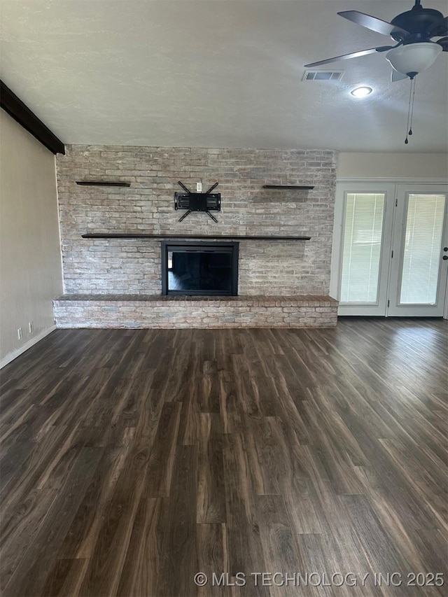 unfurnished living room featuring visible vents, a fireplace, wood finished floors, a textured ceiling, and a ceiling fan