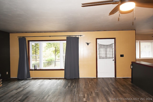 unfurnished living room with dark hardwood / wood-style flooring and ceiling fan